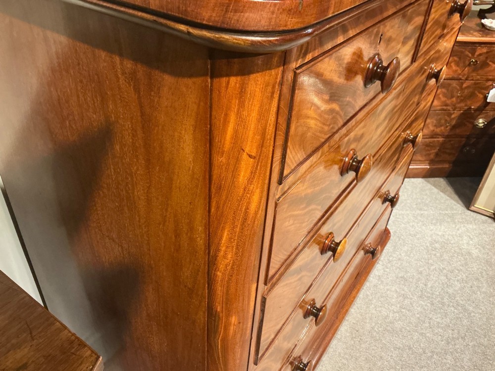 A Victorian mahogany chest of drawers featuring two short drawers over three long drawers with turned wooden knobs and flame veneer fronts. View X