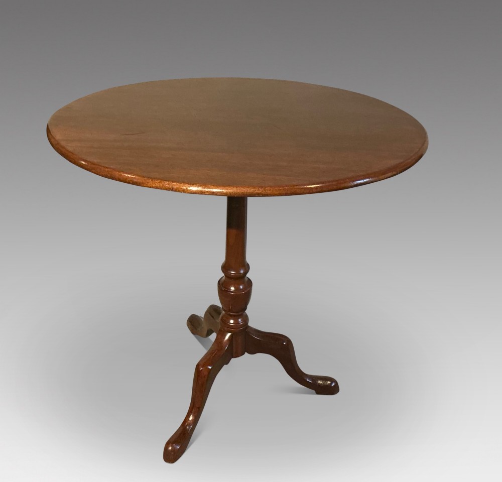 A circular mahogany tripod table featuring a turned central pedestal supported by three cabriole legs ending in pad feet.