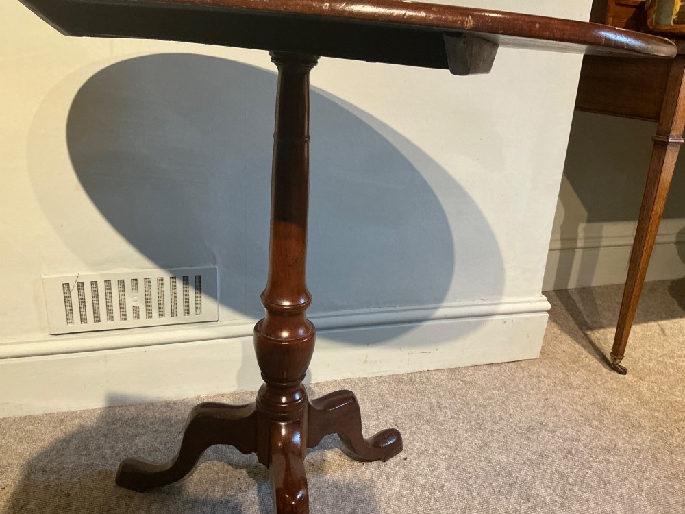 A circular mahogany tripod table featuring a turned central pedestal supported by three cabriole legs ending in pad feet. View V