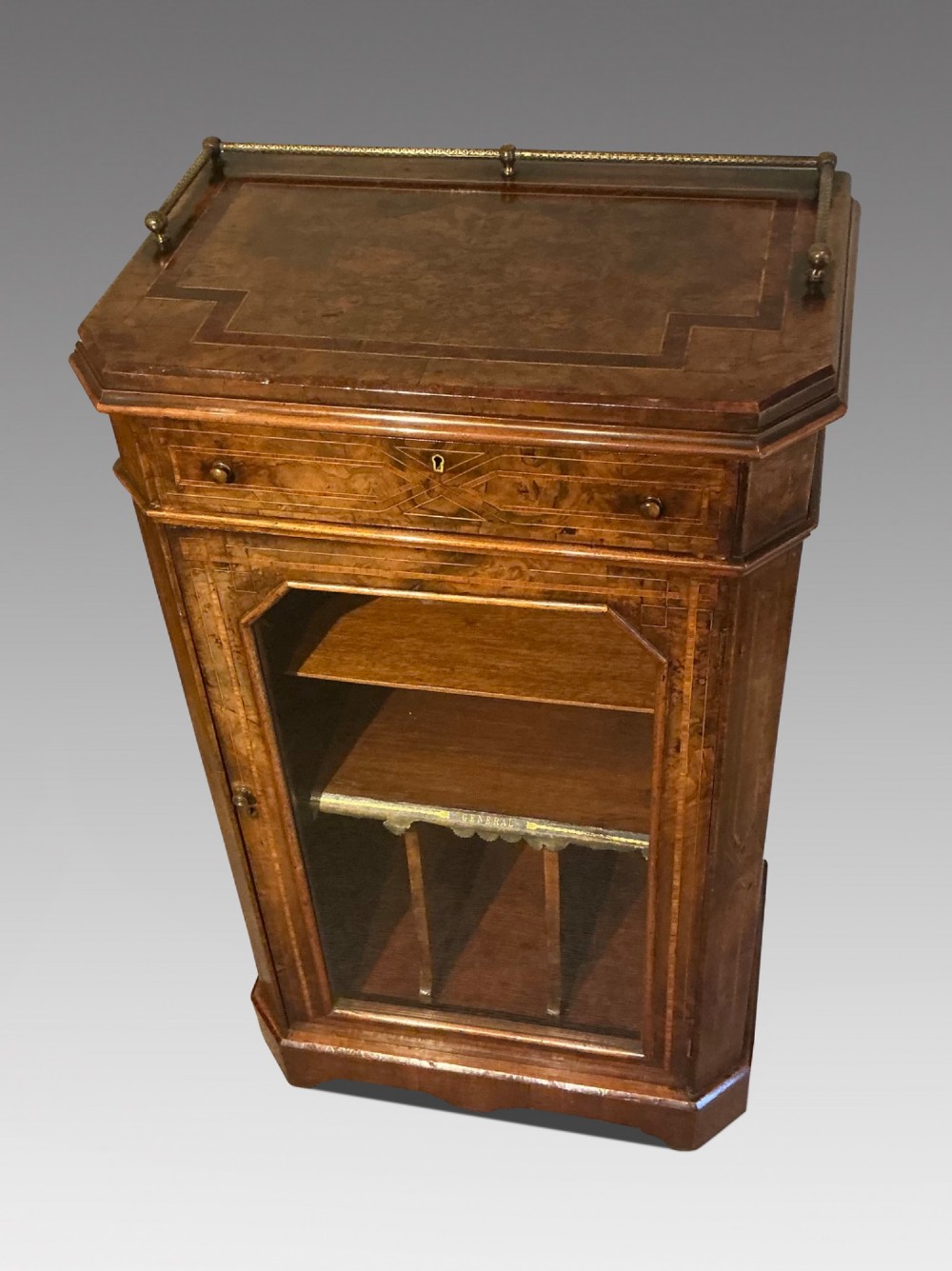 A Victorian burr walnut music cabinet featuring inlaid boxwood stringing, a top drawer, a glazed door revealing internal shelves and vertical dividers, and a brass gallery rail. View II