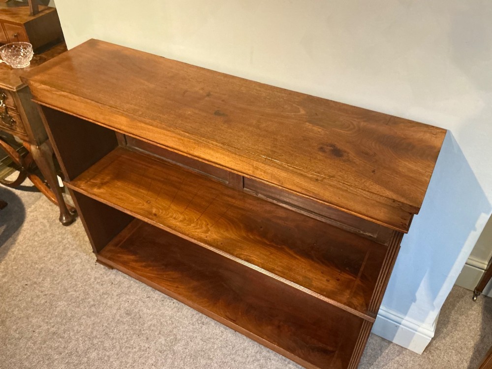 A low open mahogany bookcase featuring two wide shelves, reeded side pilasters, a panelled back, and low turned feet. View II