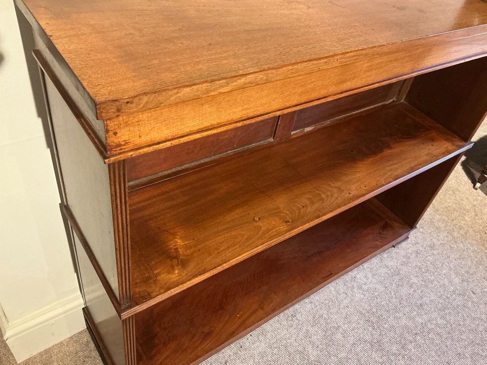 A low open mahogany bookcase featuring two wide shelves, reeded side pilasters, a panelled back, and low turned feet. View V