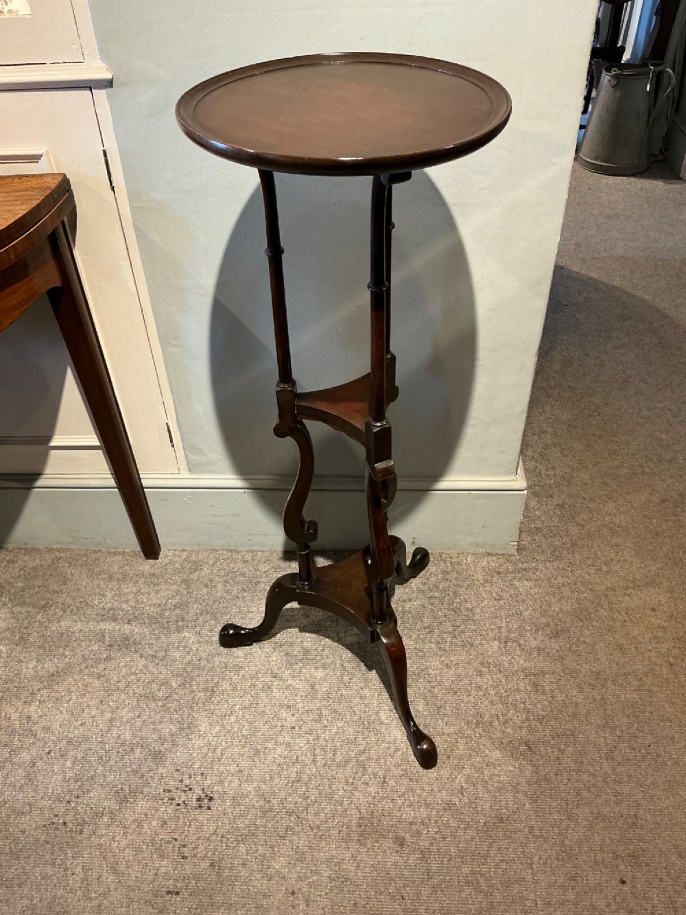 A dark mahogany torchere featuring a circular dished top supported by slender uprights, scroll details, and a tripod base with pad feet. View II