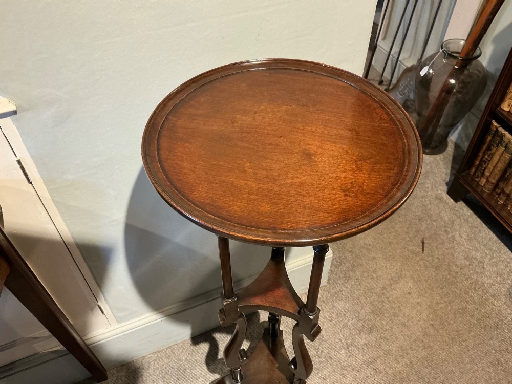 A dark mahogany torchere featuring a circular dished top supported by slender uprights, scroll details, and a tripod base with pad feet. View III
