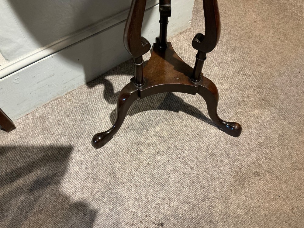 A dark mahogany torchere featuring a circular dished top supported by slender uprights, scroll details, and a tripod base with pad feet. View V