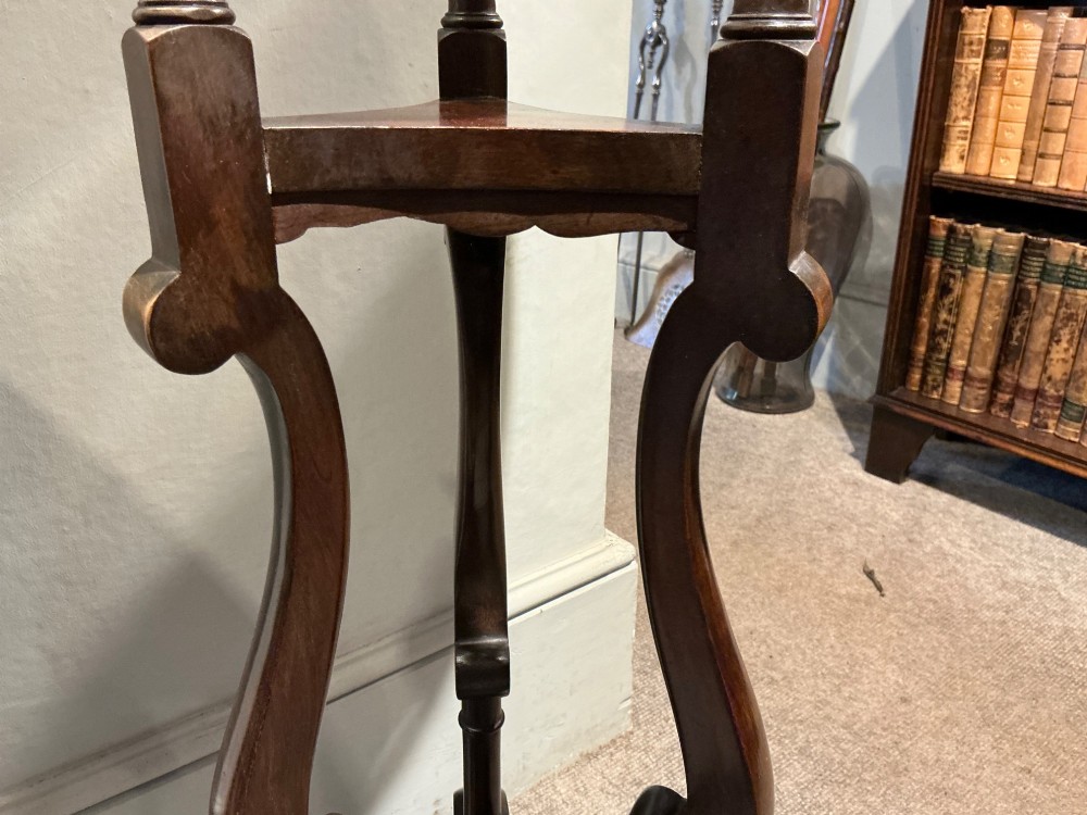 A dark mahogany torchere featuring a circular dished top supported by slender uprights, scroll details, and a tripod base with pad feet. View VI