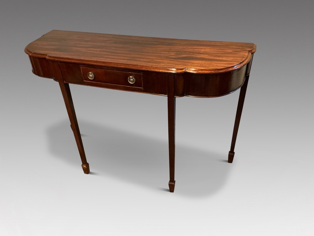 An antique mahogany hall table featuring a serpentine front, a single central drawer with brass ring handles, and four tapered square legs ending in spade feet. View II