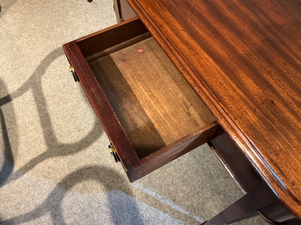 An antique mahogany hall table featuring a serpentine front, a single central drawer with brass ring handles, and four tapered square legs ending in spade feet. View VII