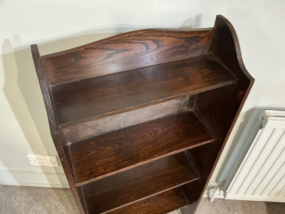 An antique dark oak open bookcase featuring four fixed shelves, cutout side panels forming feet, and a curved top cresting rail. View II