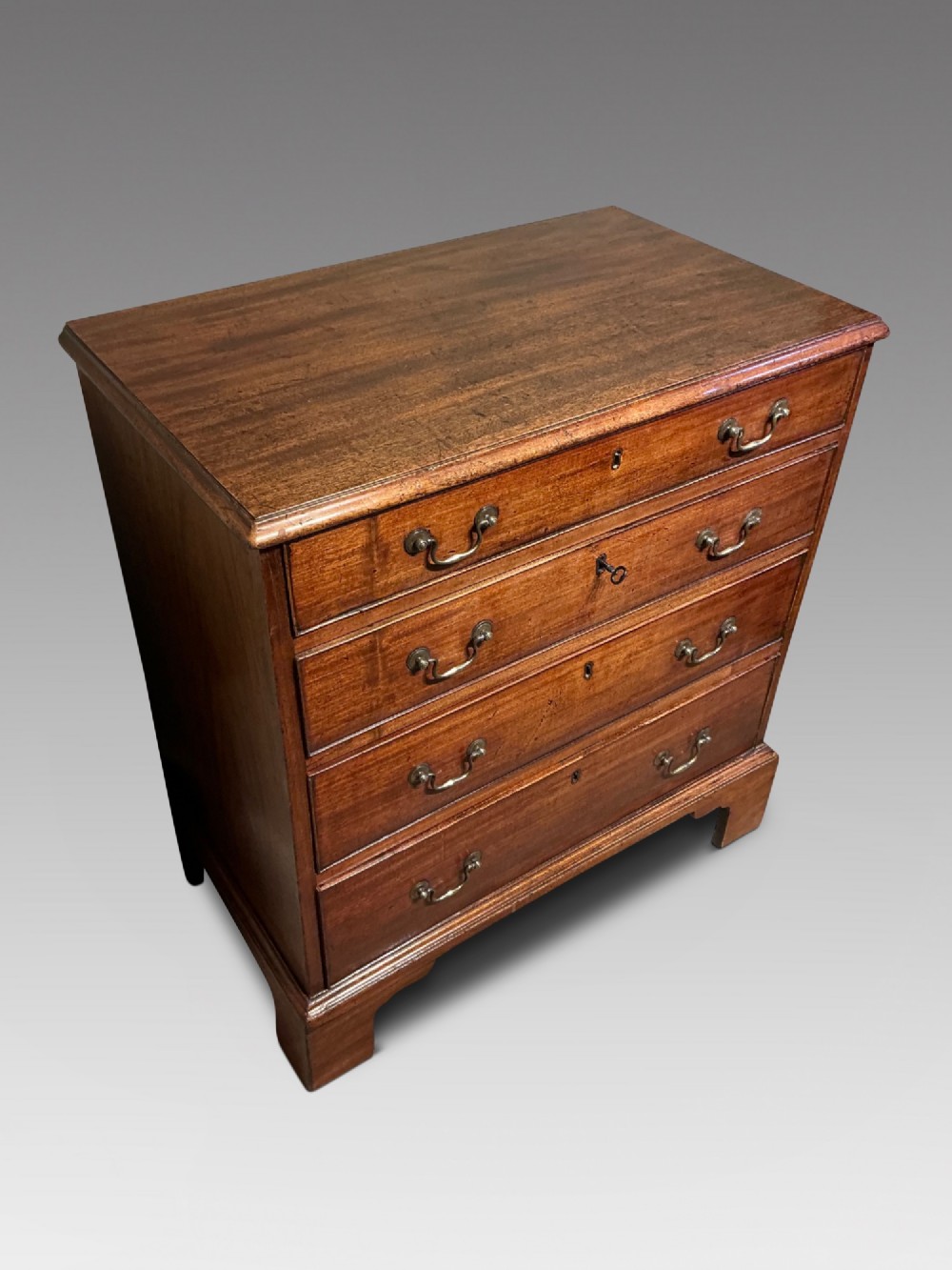 A Georgian mahogany chest of drawers featuring four graduated drawers with brass swan-neck handles and bracket feet. View II