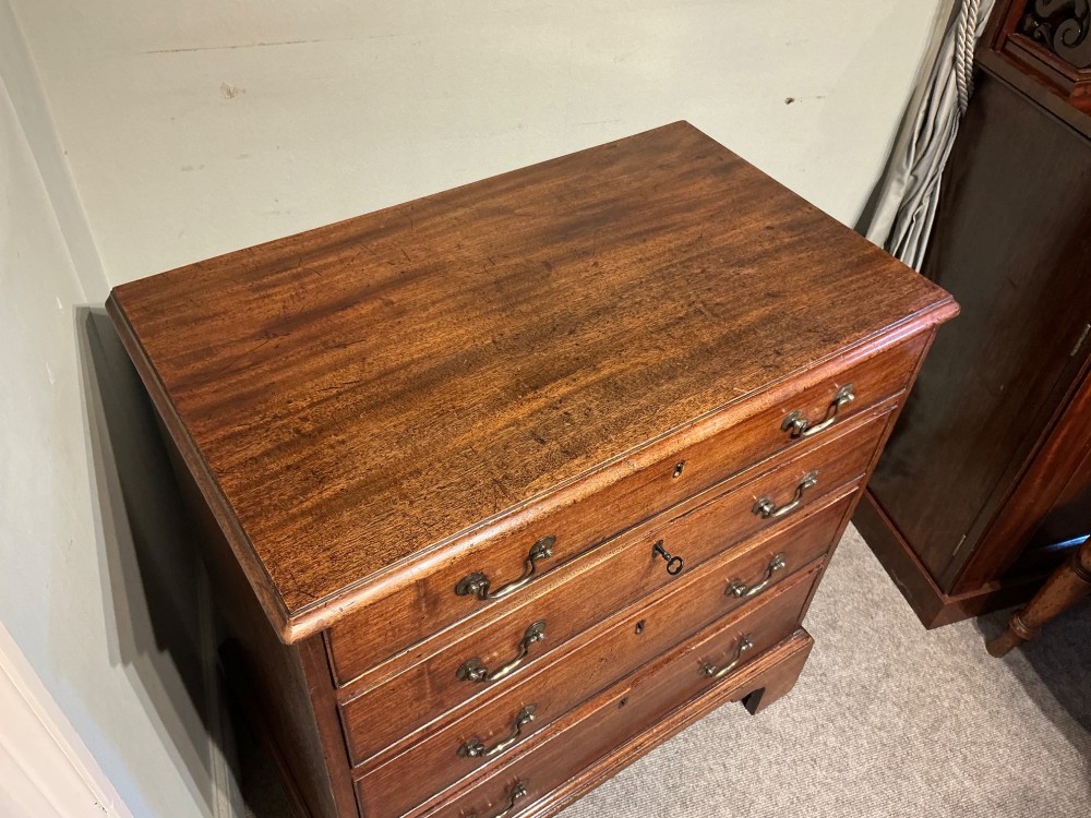 A Georgian mahogany chest of drawers featuring four graduated drawers with brass swan-neck handles and bracket feet. View III