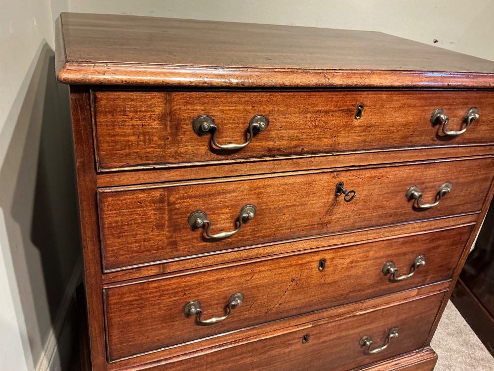 A Georgian mahogany chest of drawers featuring four graduated drawers with brass swan-neck handles and bracket feet. View IV