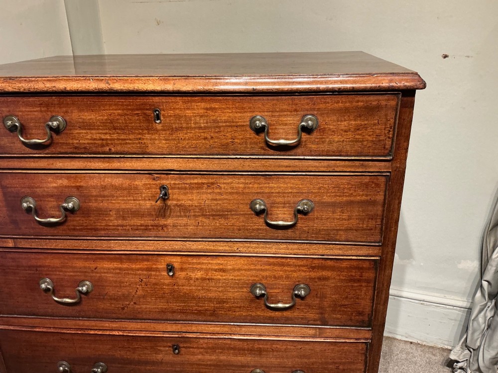 A Georgian mahogany chest of drawers featuring four graduated drawers with brass swan-neck handles and bracket feet. View VI