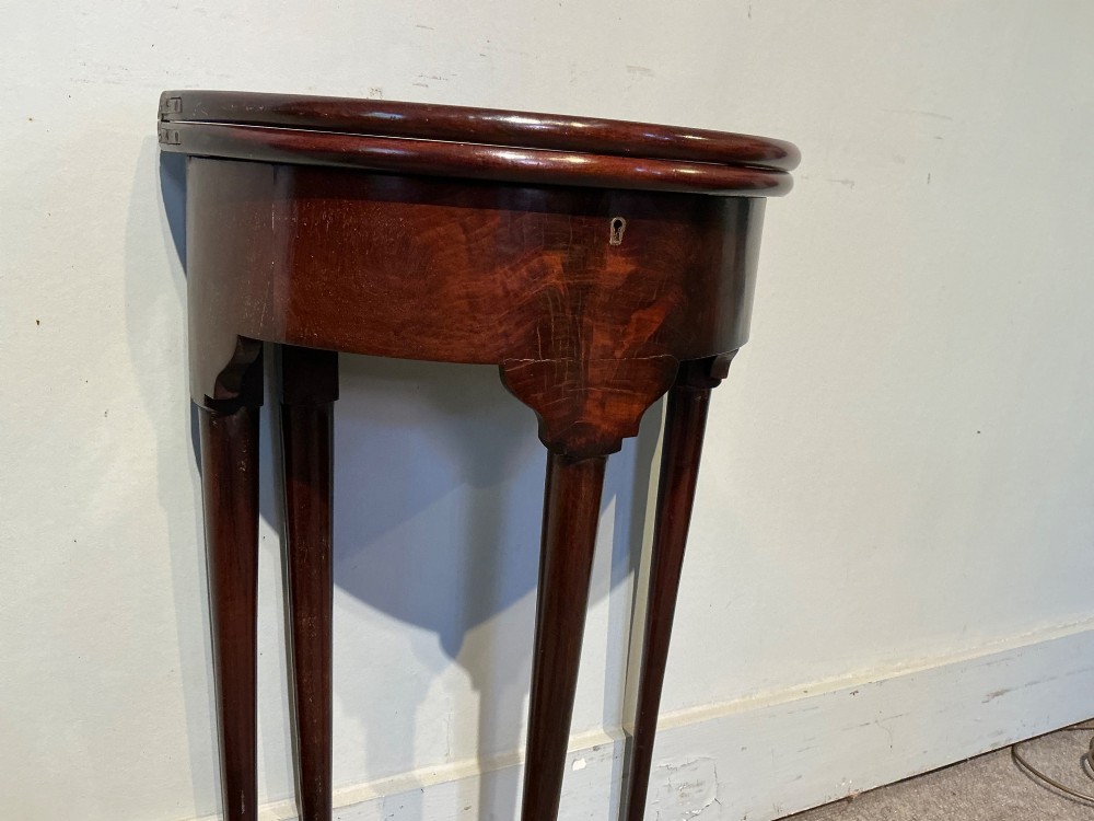 A dark mahogany demi-lune fold-over tea table with slender tapered legs, pad feet, and a brass keyhole escutcheon on the apron. View VI