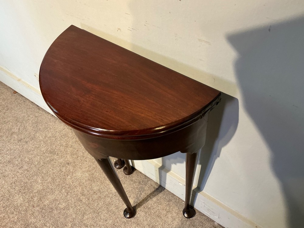 A dark mahogany demi-lune fold-over tea table with slender tapered legs, pad feet, and a brass keyhole escutcheon on the apron. View VII