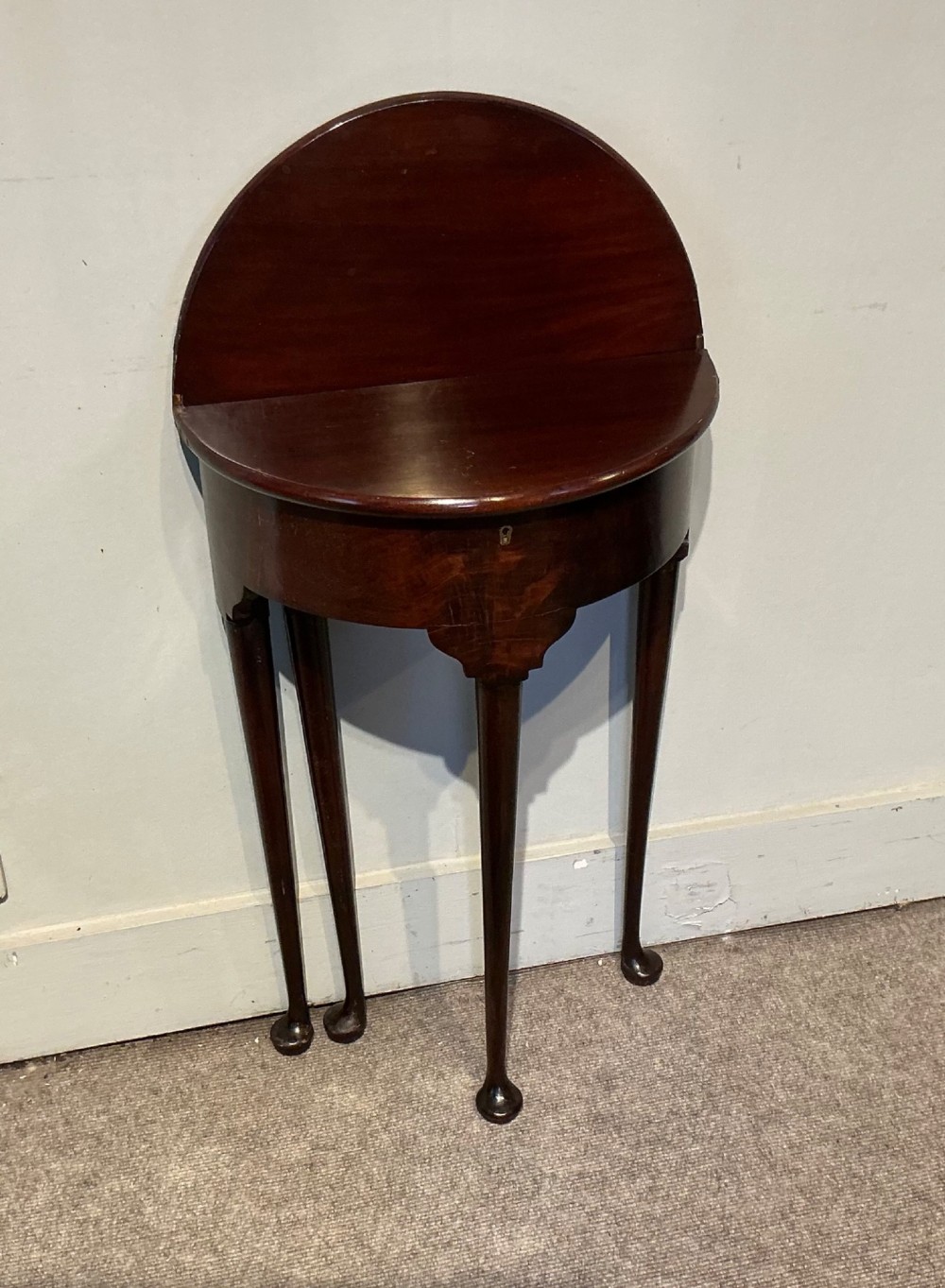 A dark mahogany demi-lune fold-over tea table with slender tapered legs, pad feet, and a brass keyhole escutcheon on the apron. View VIII