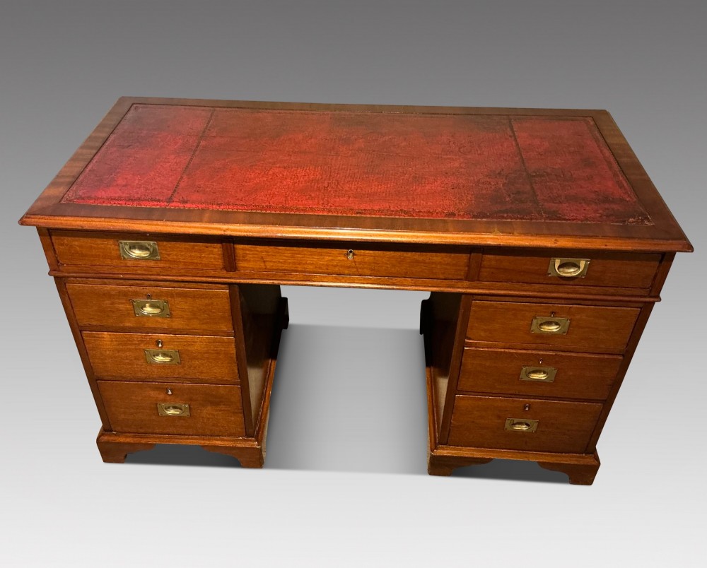 An antique mahogany pedestal desk featuring a red leather inset top, brass campaign drawer handles, and three drawers on each pedestal. View II