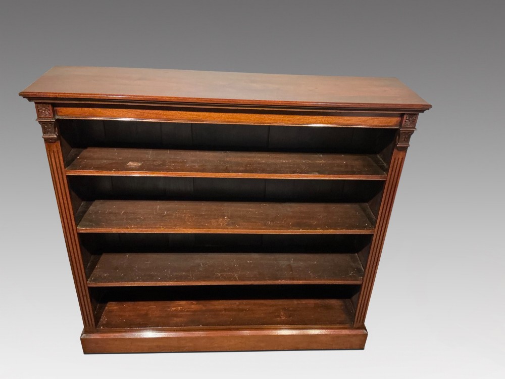An antique mahogany open bookcase featuring four fixed shelves, fluted side pilasters with carved rosette capitals, and a solid plinth base. View II
