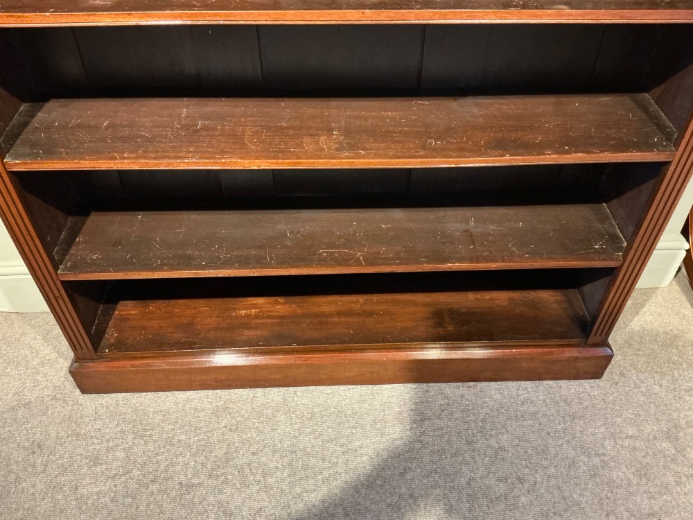 An antique mahogany open bookcase featuring four fixed shelves, fluted side pilasters with carved rosette capitals, and a solid plinth base. View VII