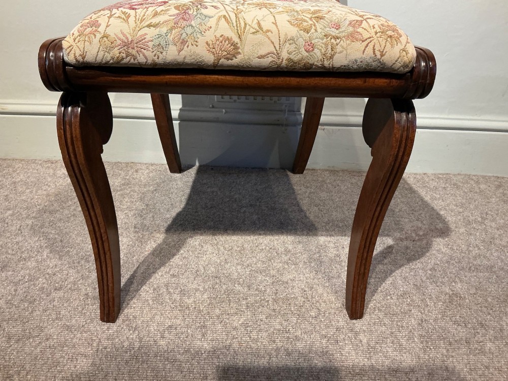 A set of four antique mahogany dining chairs with carved palmette back splats, curved crest rails, sabre legs, and floral tapestry upholstered drop-in seats. View IV