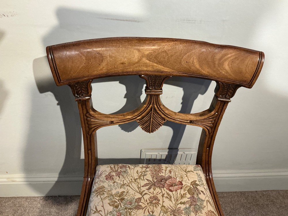 A set of four antique mahogany dining chairs with carved palmette back splats, curved crest rails, sabre legs, and floral tapestry upholstered drop-in seats. View VIII