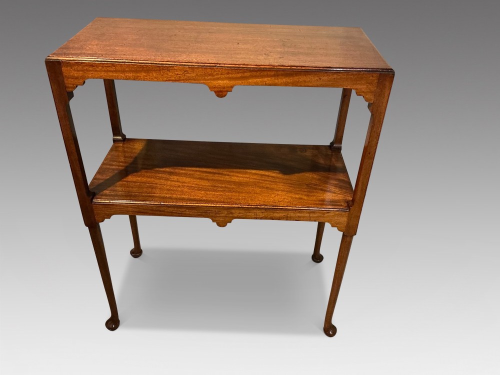 A rectangular mahogany two-tier occasional table with slender legs, pad feet, and shaped aprons.