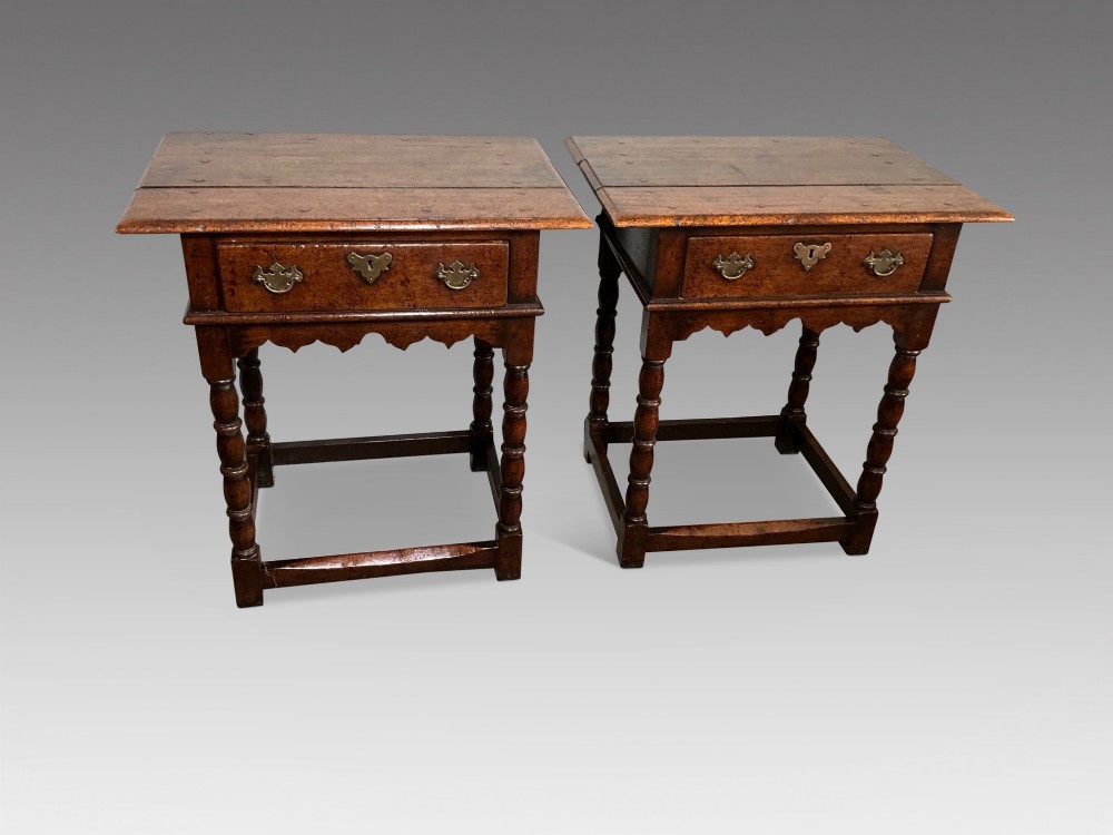A matching pair of dark brown oak side tables featuring single frieze drawers with brass handles, turned legs, and square perimeter stretchers. View II