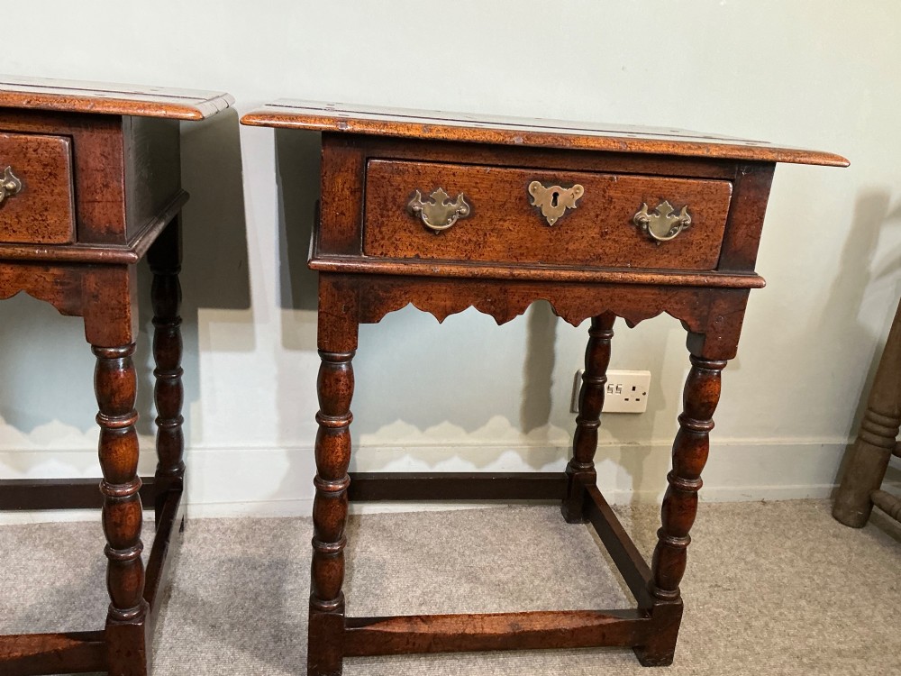A matching pair of dark brown oak side tables featuring single frieze drawers with brass handles, turned legs, and square perimeter stretchers. View IV
