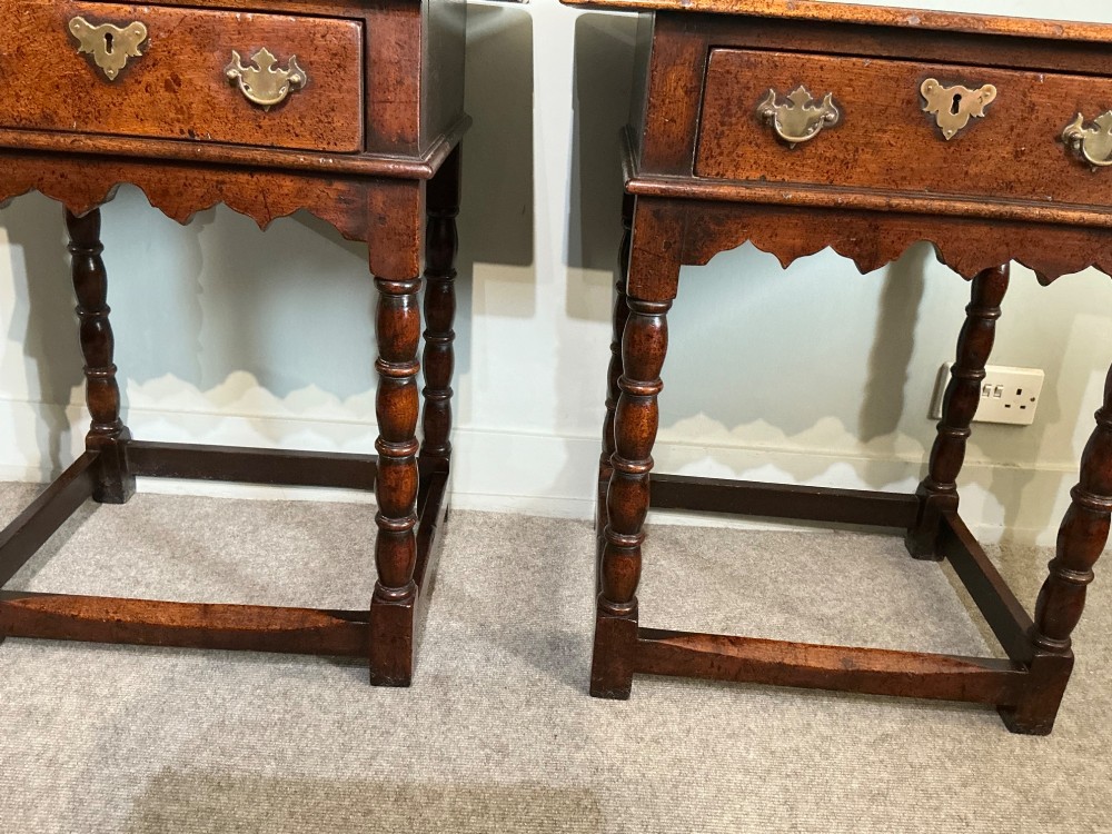 A matching pair of dark brown oak side tables featuring single frieze drawers with brass handles, turned legs, and square perimeter stretchers. View V