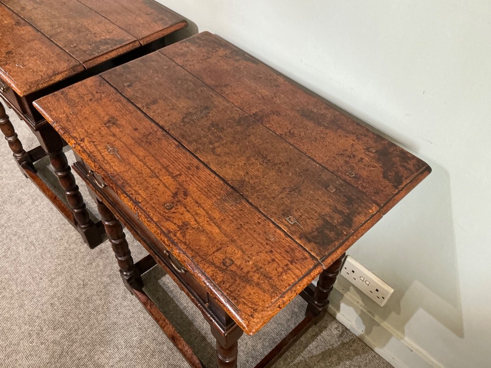 A matching pair of dark brown oak side tables featuring single frieze drawers with brass handles, turned legs, and square perimeter stretchers. View VI