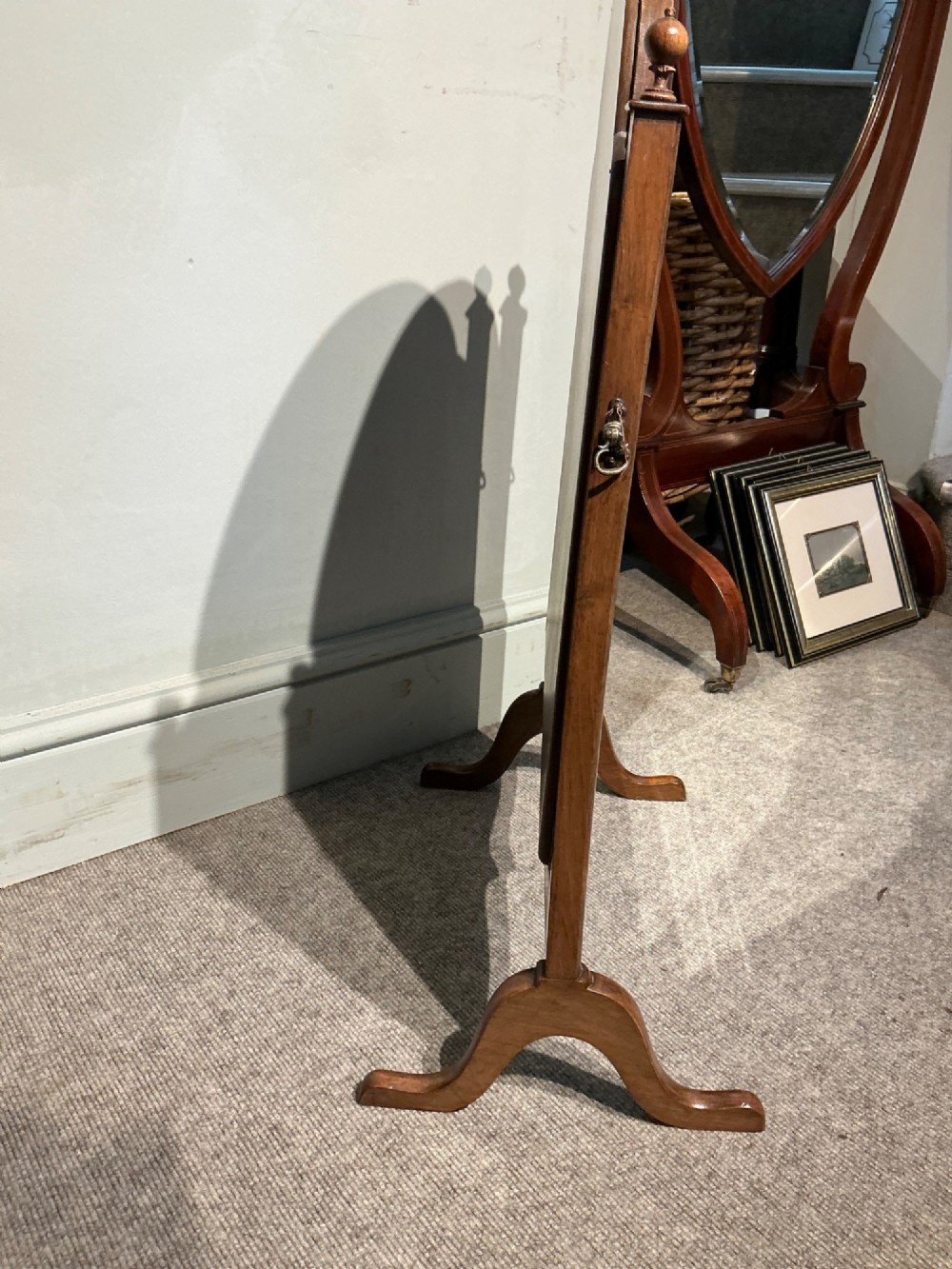 An antique arched walnut table mirror resting on vertical upright supports with turned finials and scrolled feet. View V