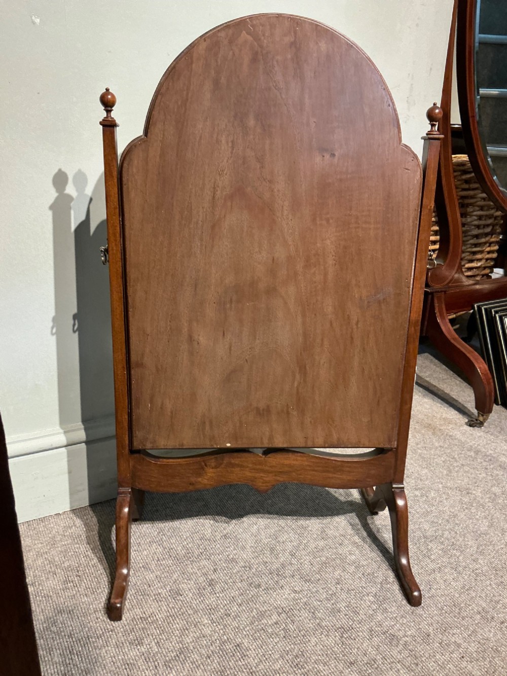 An antique arched walnut table mirror resting on vertical upright supports with turned finials and scrolled feet. View VI