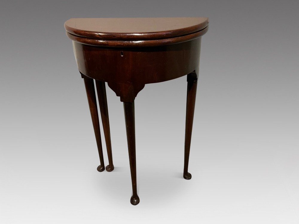 A dark mahogany demi-lune console table featuring a fold-over top, straight apron, and slender tapered legs ending in pad feet.