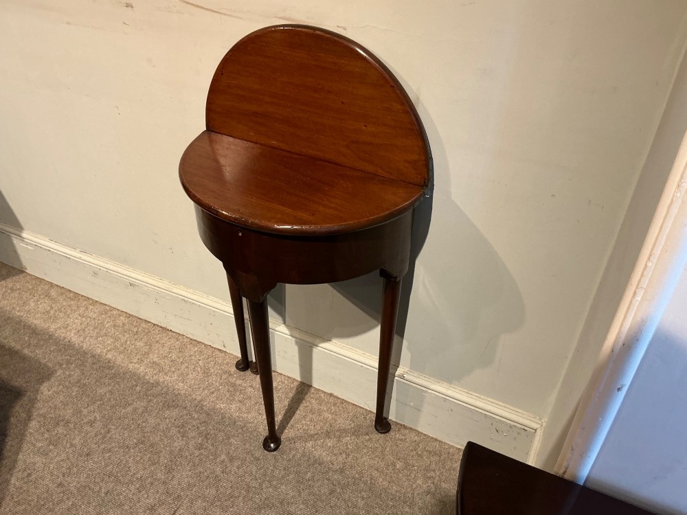 A dark mahogany demi-lune console table featuring a fold-over top, straight apron, and slender tapered legs ending in pad feet. View III