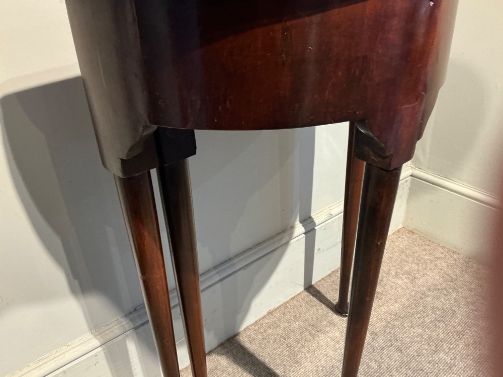 A dark mahogany demi-lune console table featuring a fold-over top, straight apron, and slender tapered legs ending in pad feet. View V