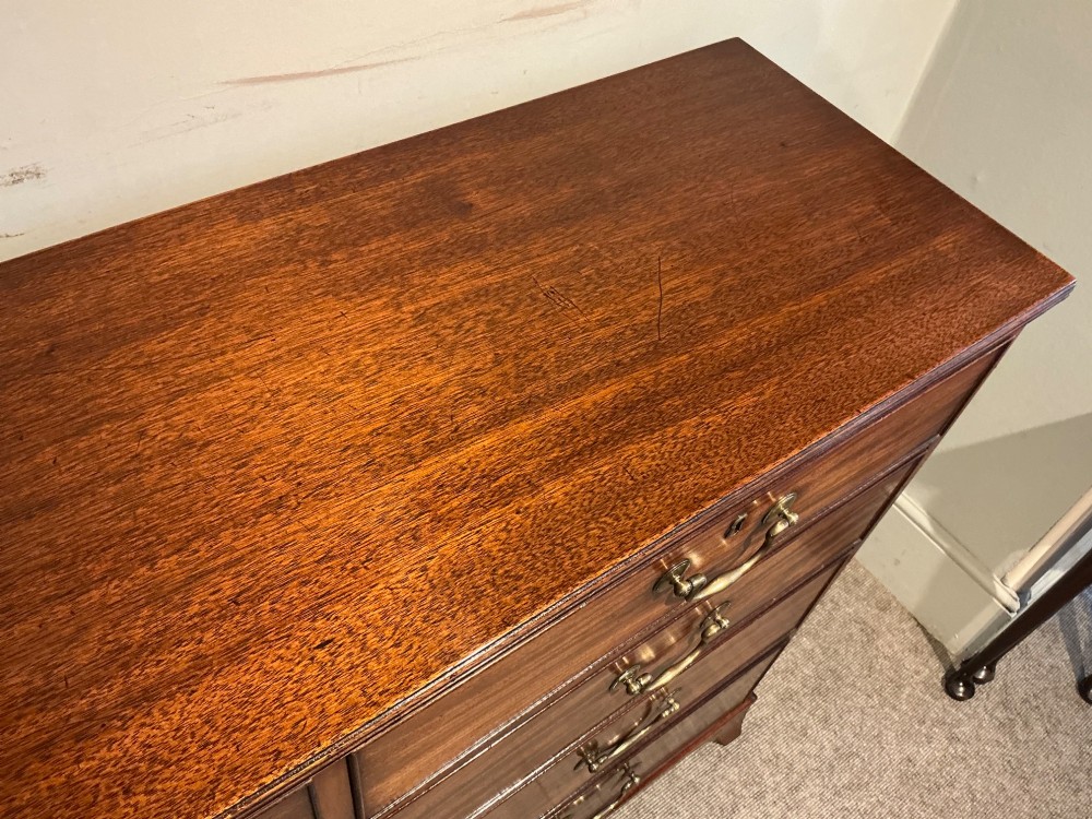 A Georgian mahogany chest of drawers featuring two short over three long graduated drawers with brass swan-neck handles and bracket feet. View II