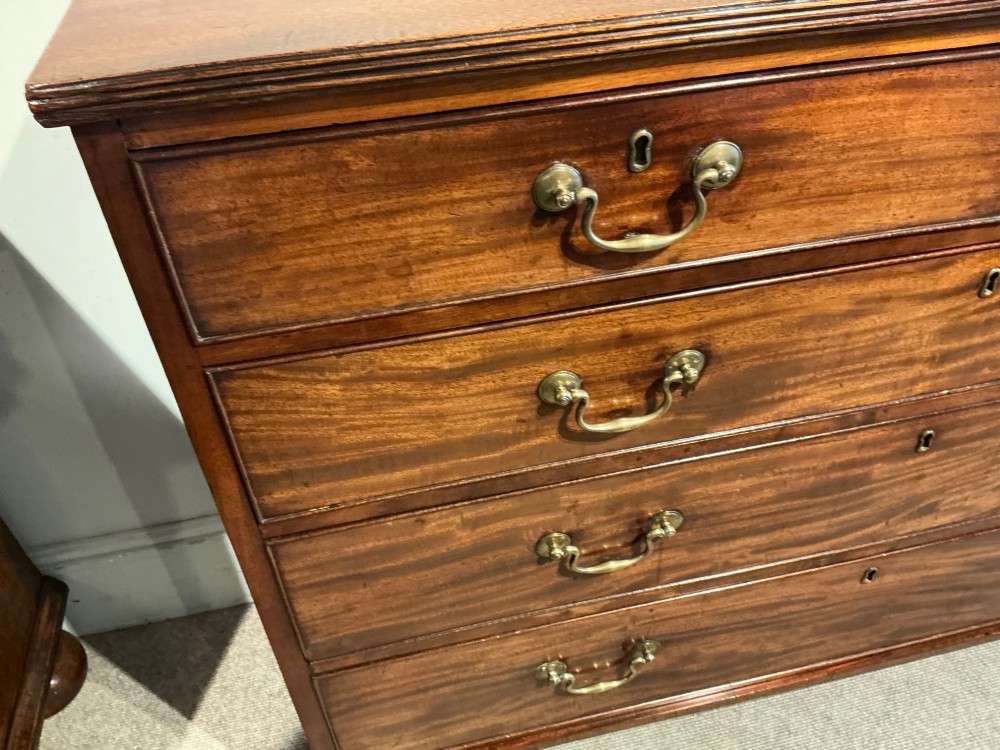 A Georgian mahogany chest of drawers featuring two short over three long graduated drawers with brass swan-neck handles and bracket feet. View IV