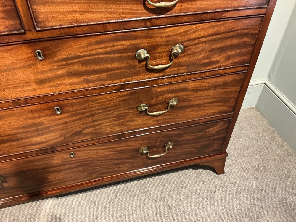 A Georgian mahogany chest of drawers featuring two short over three long graduated drawers with brass swan-neck handles and bracket feet. View VI