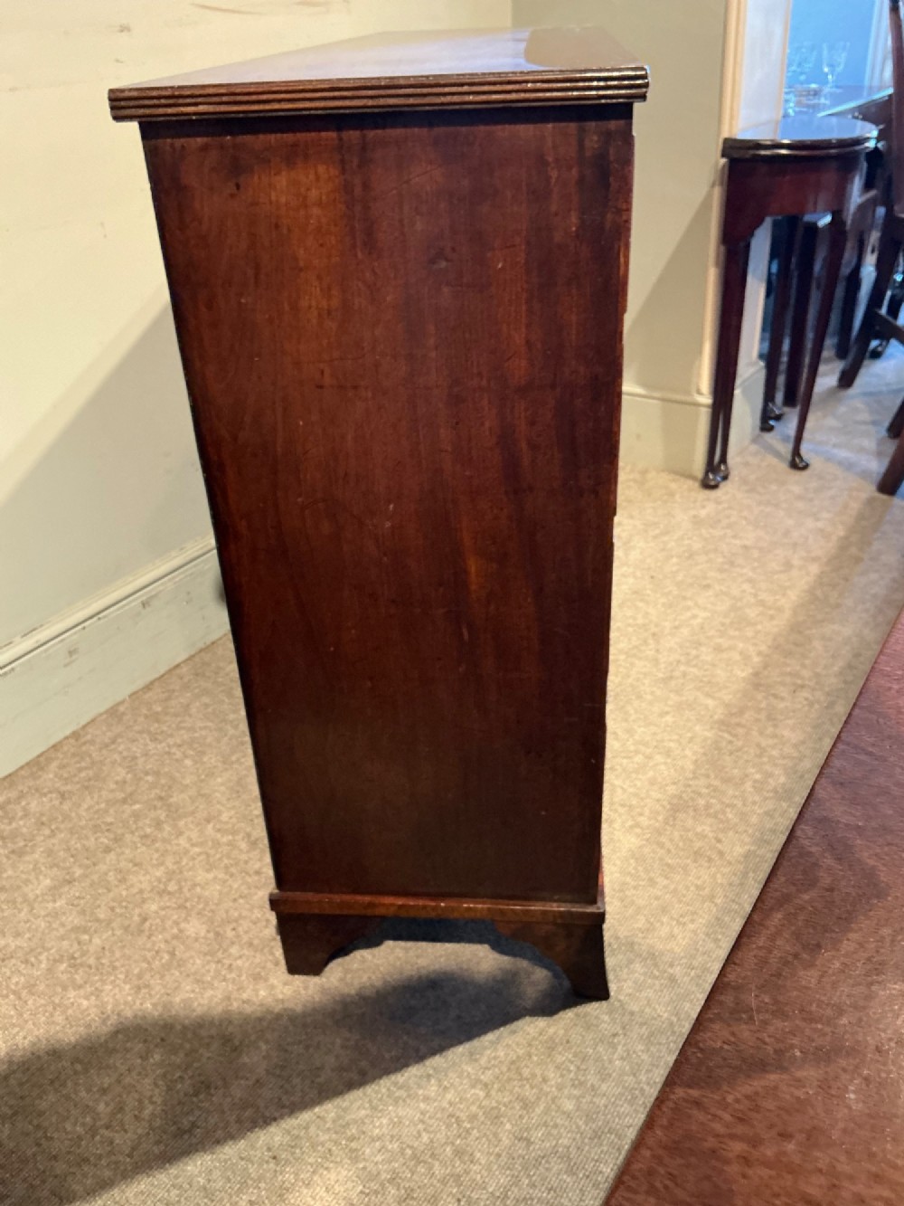 A Georgian mahogany chest of drawers featuring two short over three long graduated drawers with brass swan-neck handles and bracket feet. View VII