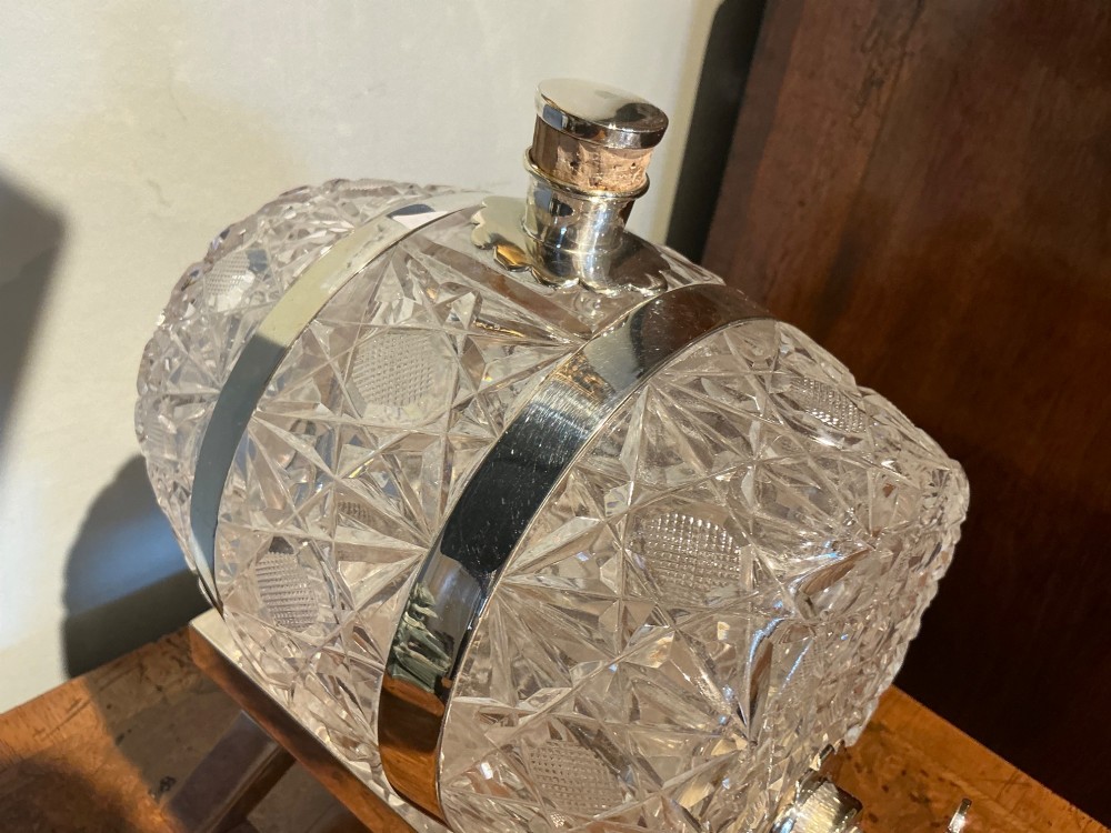 A Victorian cut crystal spirit barrel featuring geometric diamond patterns, silver-plated hoops, a metal tap, and a stopper, resting on a four-legged silvered stand. View II