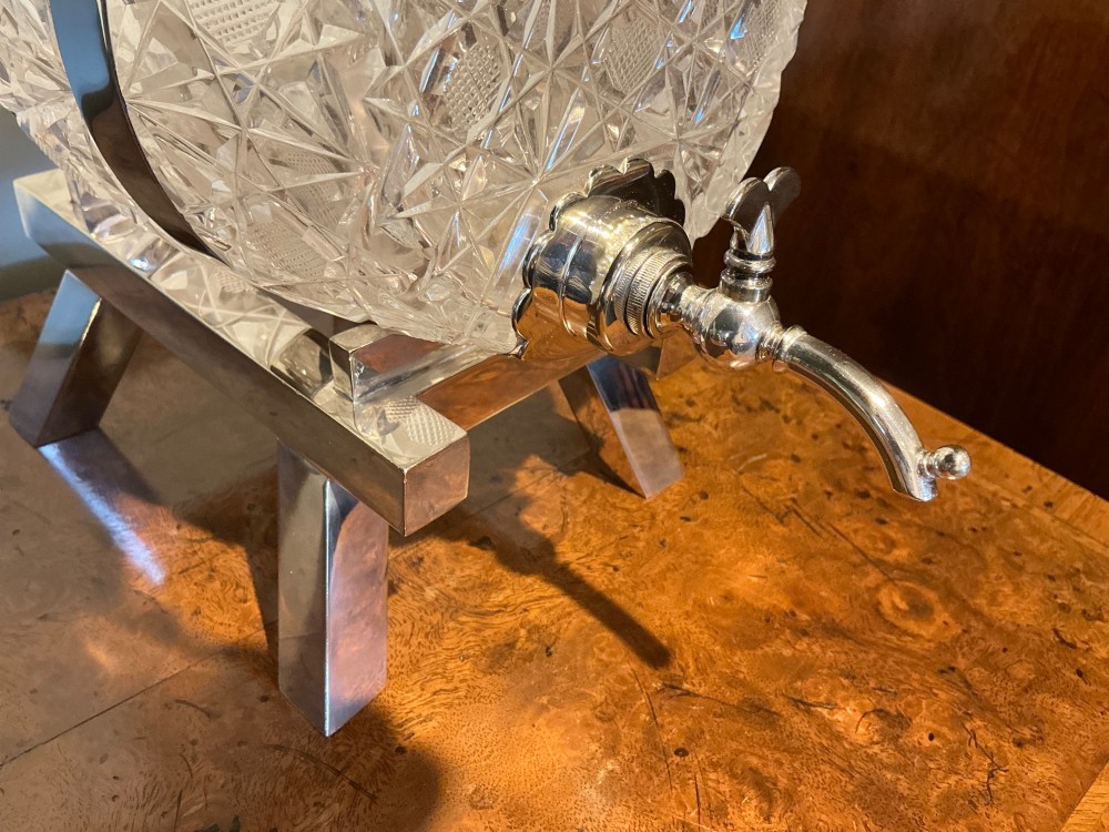 A Victorian cut crystal spirit barrel featuring geometric diamond patterns, silver-plated hoops, a metal tap, and a stopper, resting on a four-legged silvered stand. View III