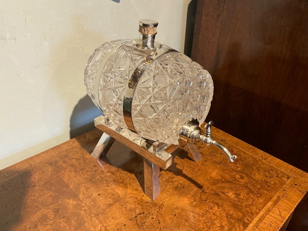 A Victorian cut crystal spirit barrel featuring geometric diamond patterns, silver-plated hoops, a metal tap, and a stopper, resting on a four-legged silvered stand. View IV