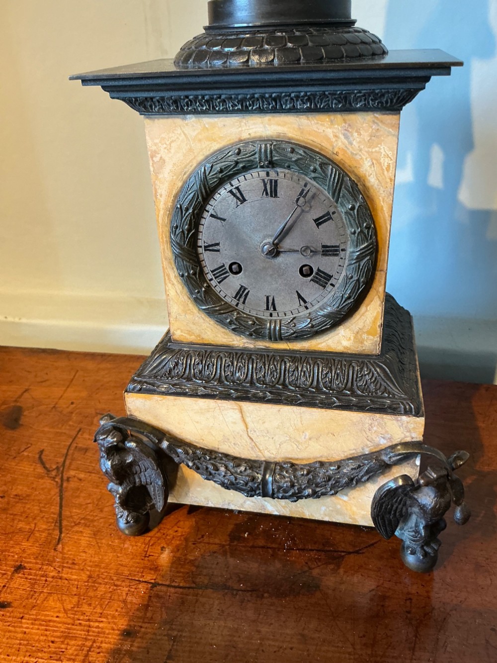 A French Empire style mantel clock featuring a dark patinated bronze figure of Napoleon standing above a yellow marble plinth housing a circular metal dial. View IV