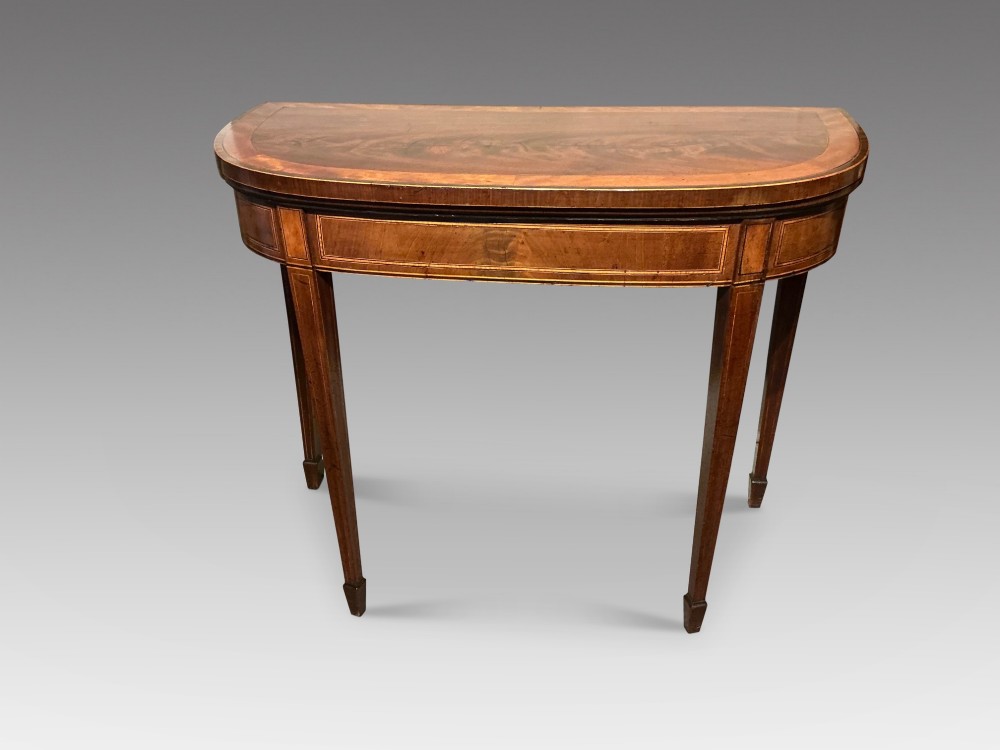 A D-shaped Georgian mahogany fold-over card table featuring flame mahogany veneers, contrasting inlay stringing, and tapered square legs. View II