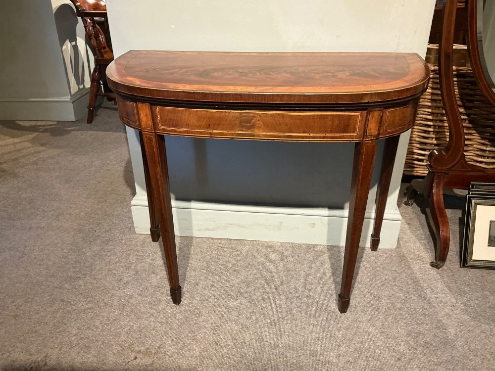 A D-shaped Georgian mahogany fold-over card table featuring flame mahogany veneers, contrasting inlay stringing, and tapered square legs. View III