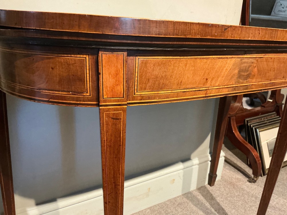 A D-shaped Georgian mahogany fold-over card table featuring flame mahogany veneers, contrasting inlay stringing, and tapered square legs. View VI