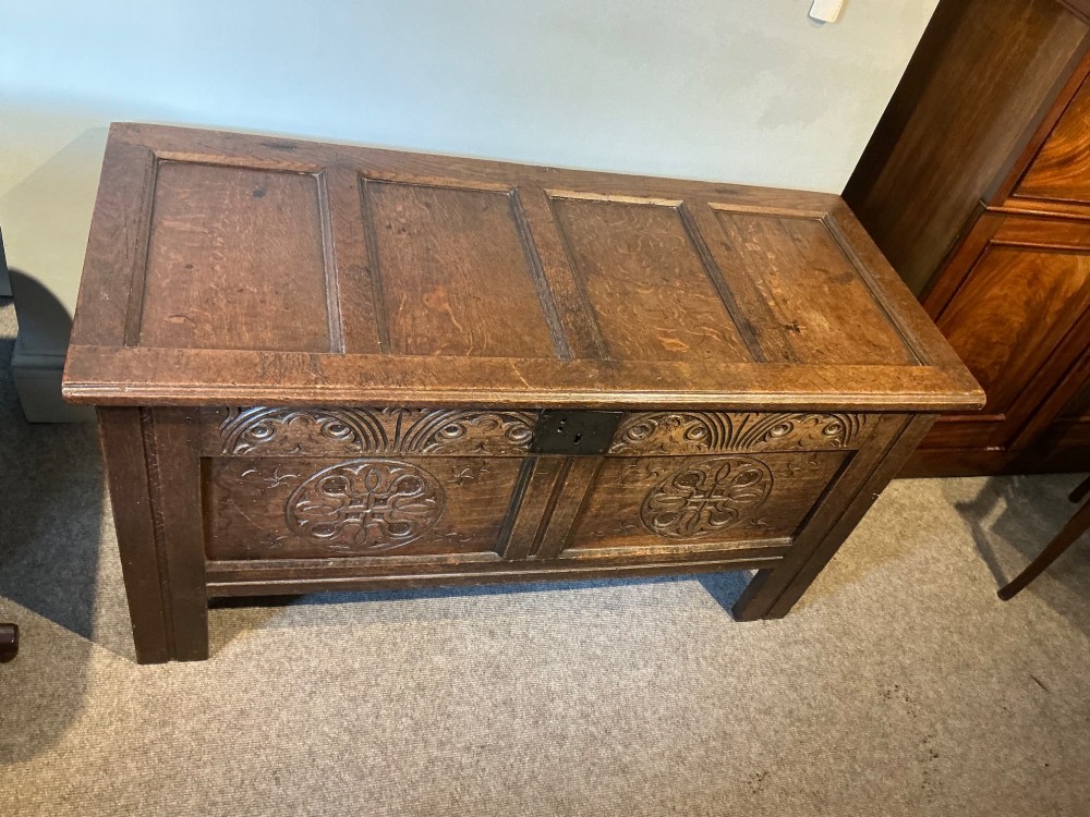 A 17th-century carved oak coffer with a four-panel lid, carved lunette top rail, roundel carved front panels, and a central iron lockplate. View II