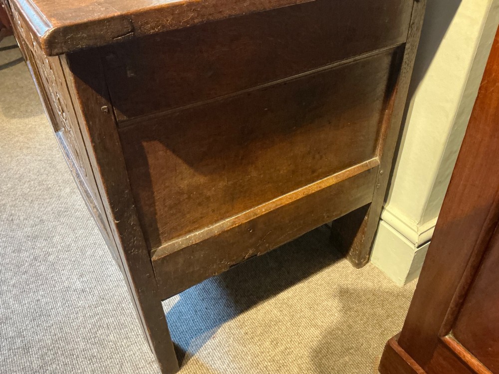 A 17th-century carved oak coffer with a four-panel lid, carved lunette top rail, roundel carved front panels, and a central iron lockplate. View VII
