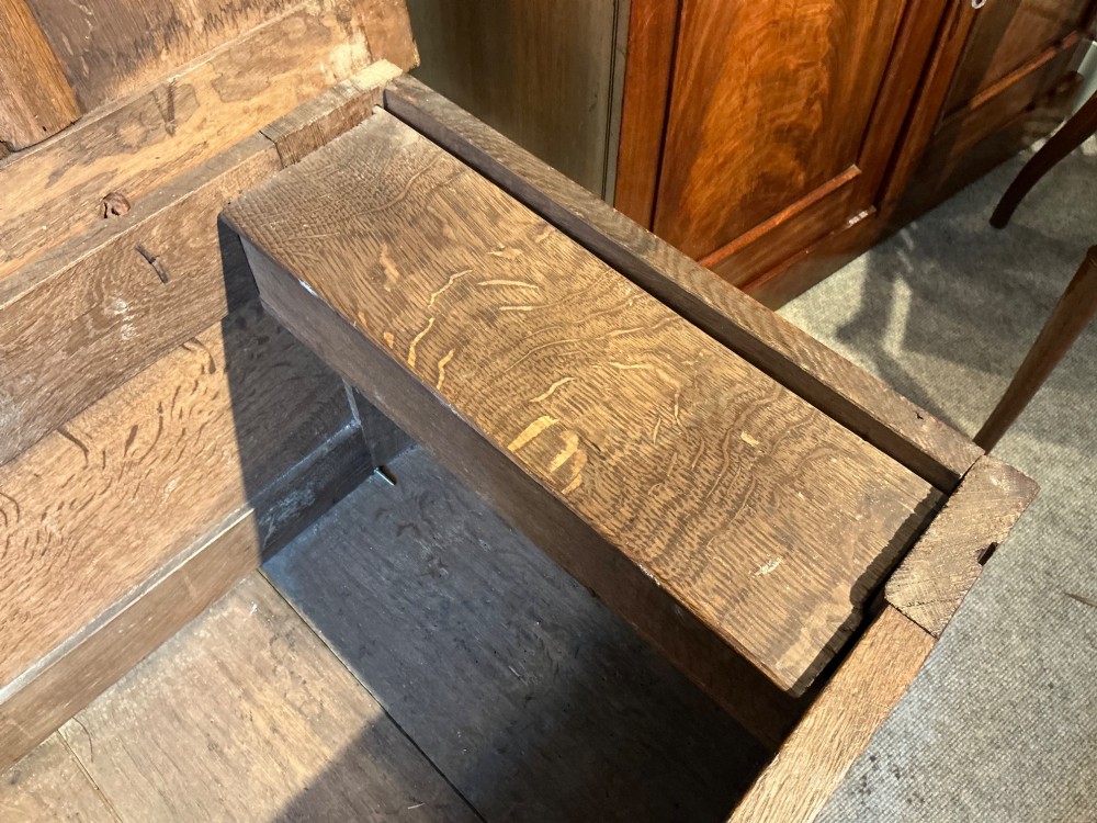 A 17th-century carved oak coffer with a four-panel lid, carved lunette top rail, roundel carved front panels, and a central iron lockplate. View VIII