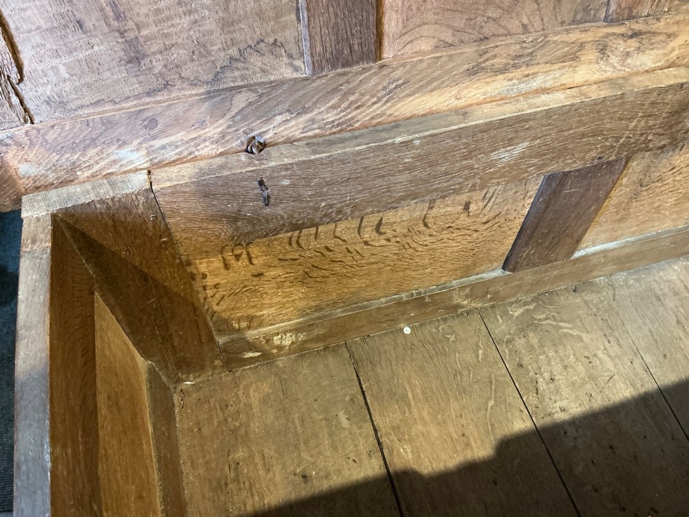 A 17th-century carved oak coffer with a four-panel lid, carved lunette top rail, roundel carved front panels, and a central iron lockplate. View IX
